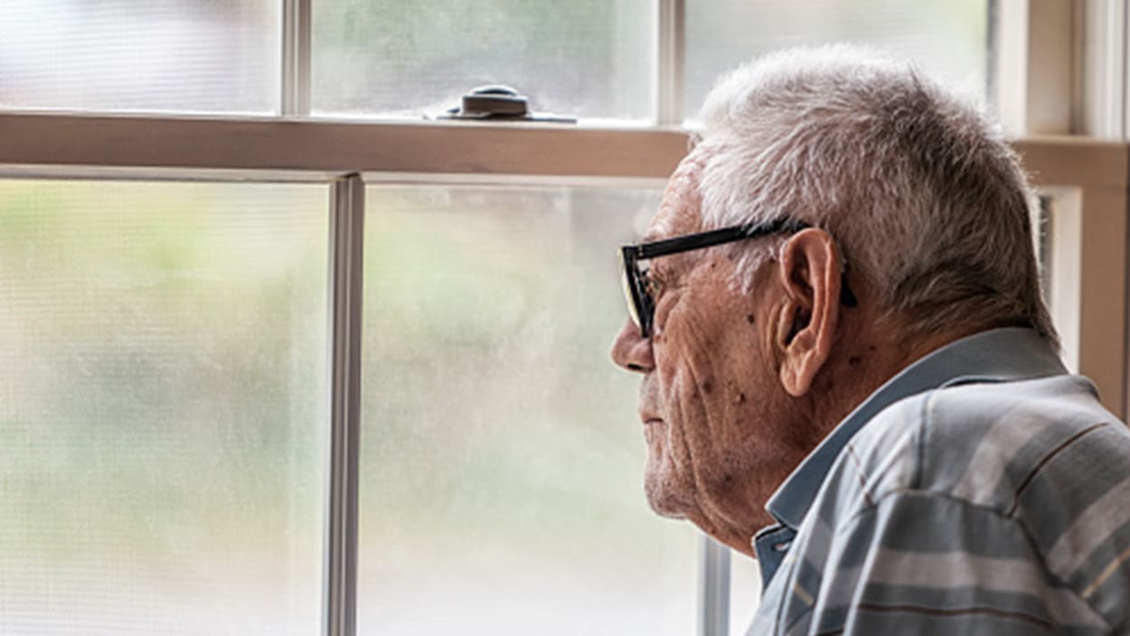 Elderly man looking out a window