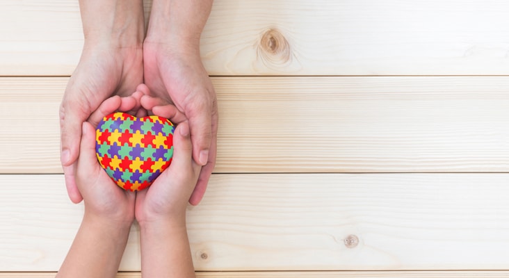 hand in hand holding heart with puzzle graphic