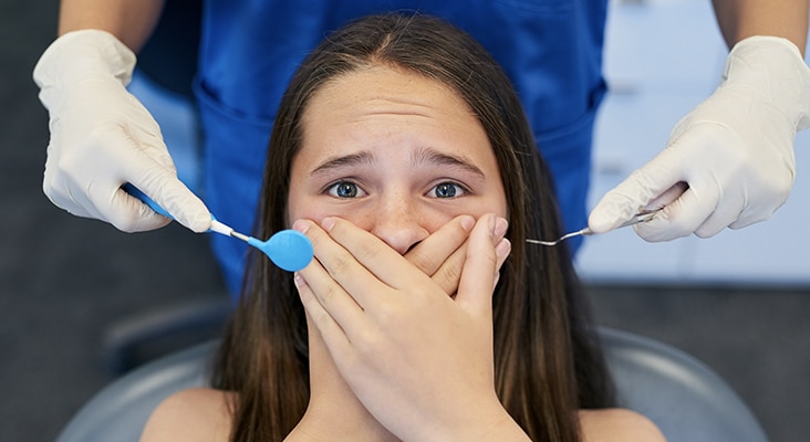 scared girl covering mouth in dentist chair