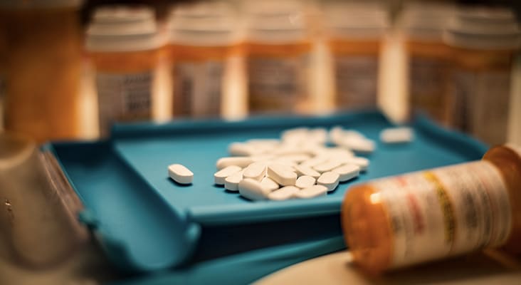 Unsorted prescription pills sit in a pharmacist's counting tray before they are bottled.