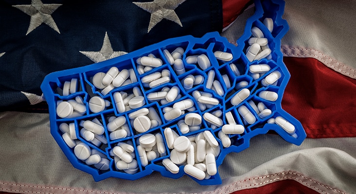 Healthcare, opioid epidemic and drug abuse concept with the map of USA filled with oxycodone and hydrocodone pharmaceutical pills on the American flag