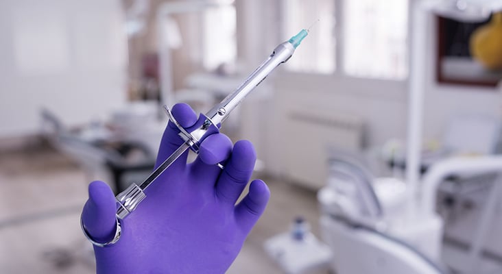 Hand of dentist holding dental syringe