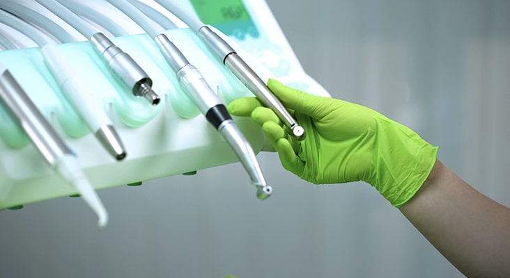 Dentist in gloves choosing handpiece for procedure, modern equipment in clinic