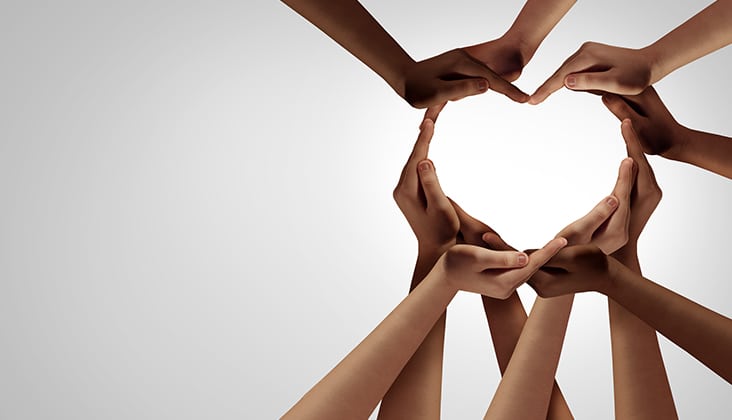 Unity and diversity partnership as heart hands in a group of diverse people connected together shaped as a support symbol expressing the feeling of teamwork and togetherness.