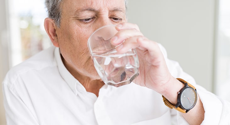 Handsome senior man drinking a fresh glass of water at home