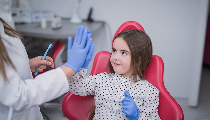 Dentist giving girl in dental chair a high five