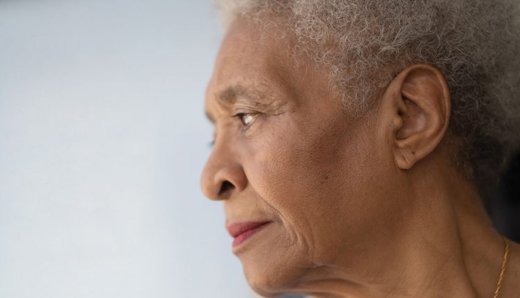 Older adult woman looking out of window
