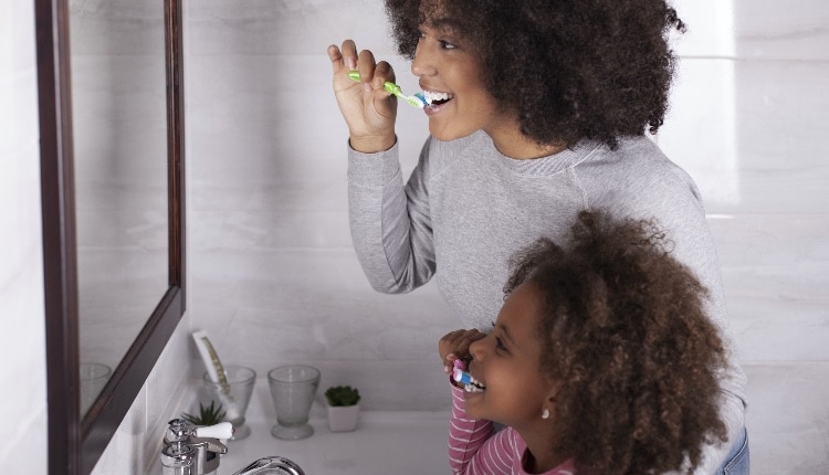 Mother and daughter are brushing their teeth in the bathroom