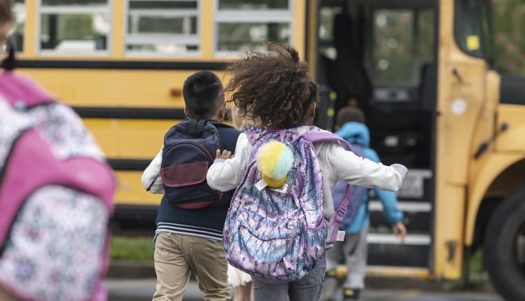 Diverse group of happy children getting on school bus