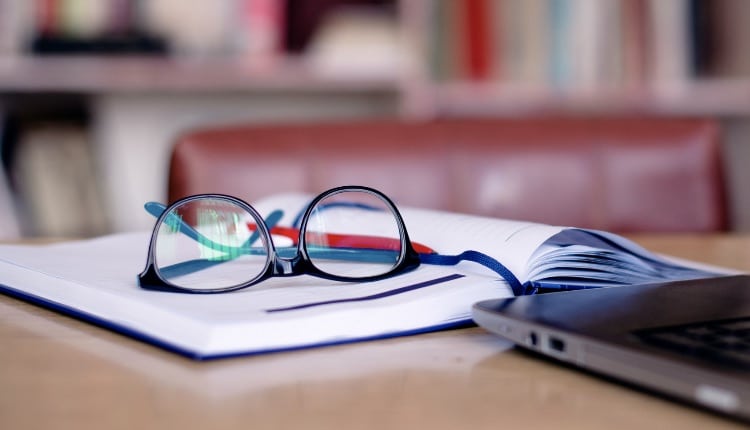 Office tools for school project: laptop, book, eyeglasses.