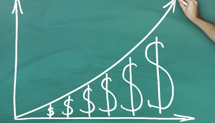 Hand holding chalk dollar growth chart on green blackboard