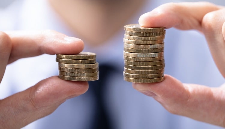 Man Holding Two Coin Stacks To Compare