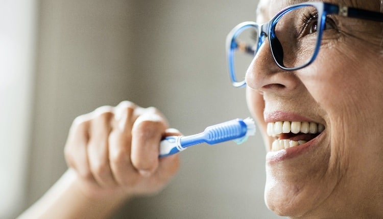 Close up of happy mature woman brushing her teeth