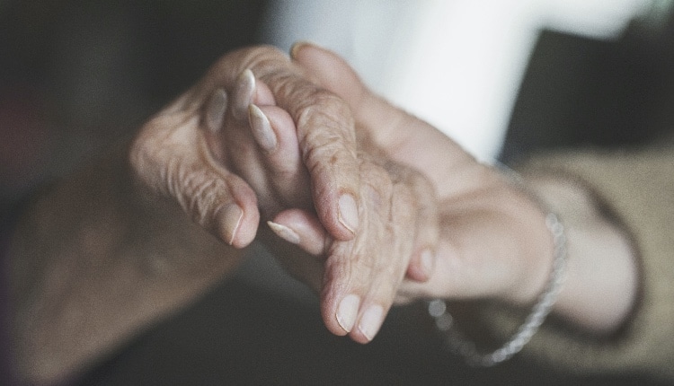 home caregiver holding hand of very old woman