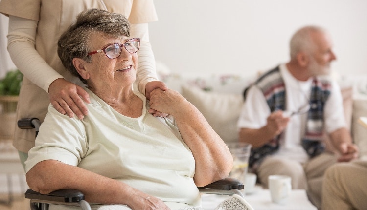 Happy senior lady sitting at wheelchair in nursing home for elderly