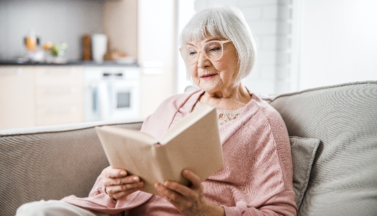 Senior woman in glasses reading book at home