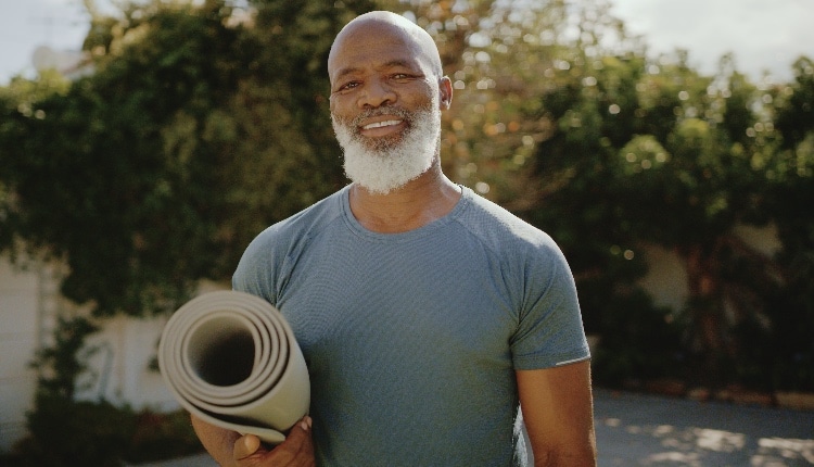 Cropped portrait of a happy senior man standing alone before a yoga session in his back garden