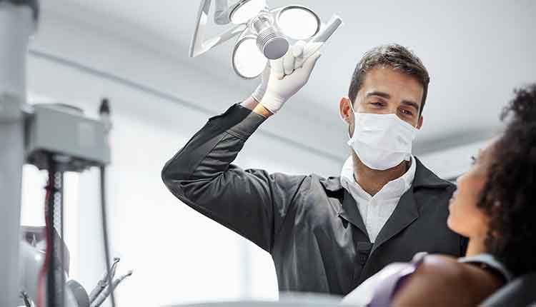 Dentist adjusting surgical light in dental clinic