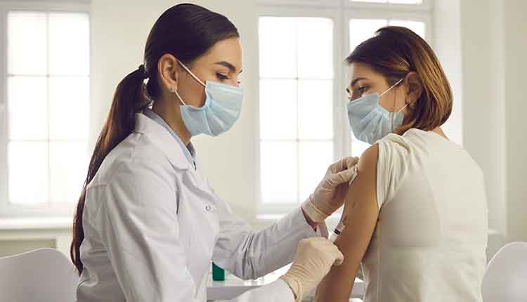 Young woman in face mask getting an antiviral vaccine at the hospital or health center