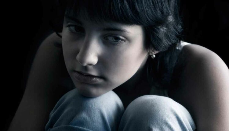 Girl sitting in dark room feeling depressed