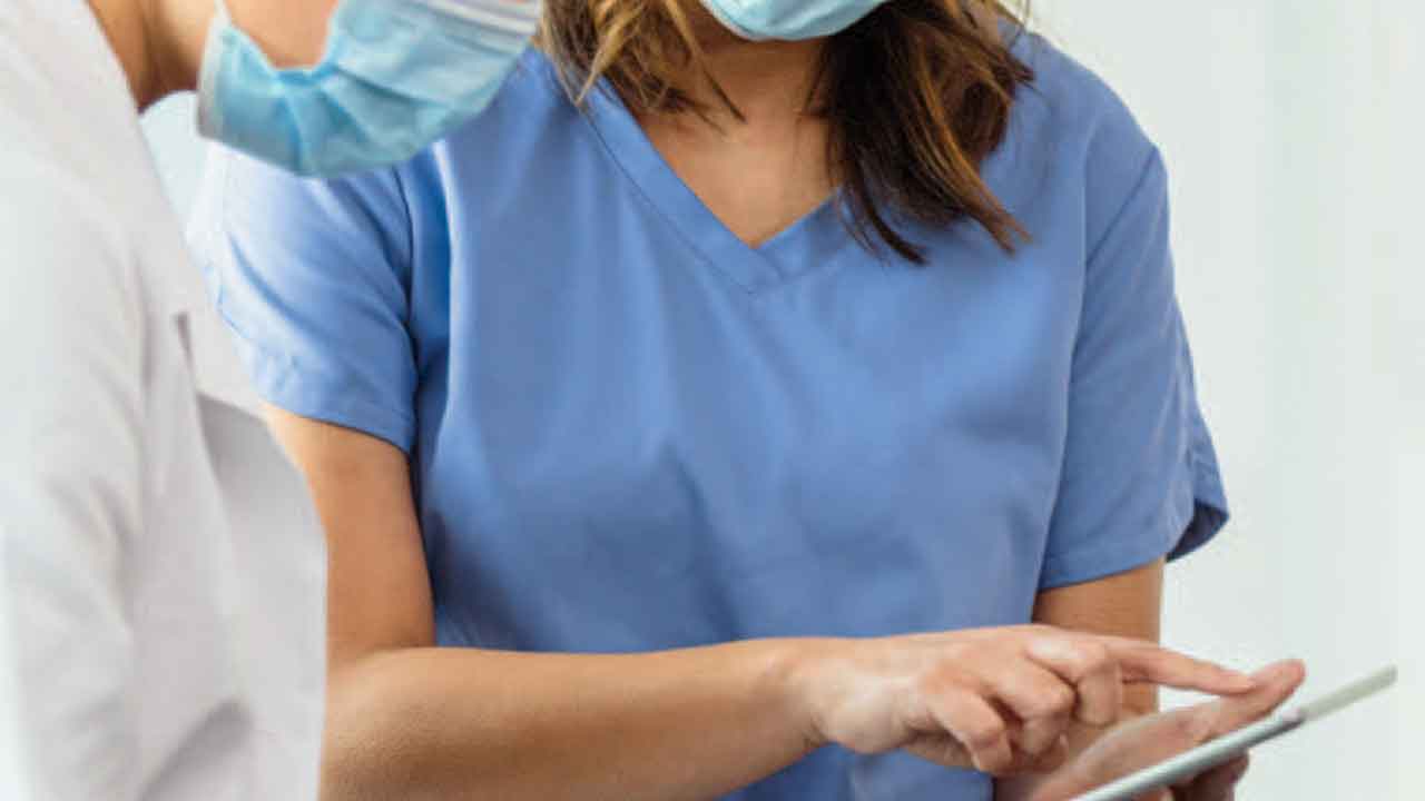 Female dentist and dental hygienist using a tablet