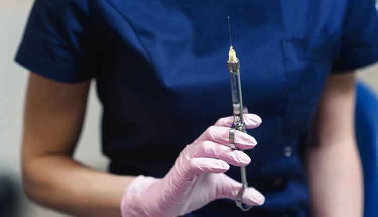 Doctor holding in her dentist's hand carpool syringe for local anesthesia on background isolated