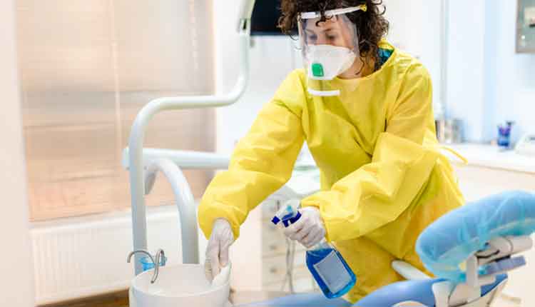 Dentist assistant using strong disinfectant agent to clean dental office for the next patient