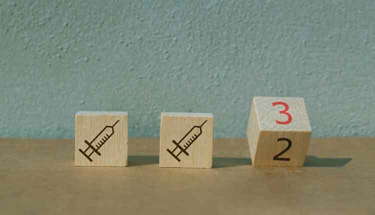Illustration of booster shot for mRNA vaccines for Covid-19 with wooden block flipping from 2 to 3. Two wooden blocks with syringes.