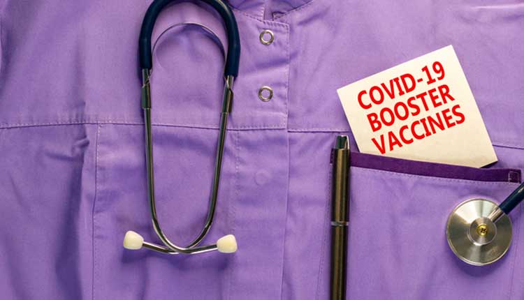 Covid-19 booster shots vaccines symbol. Medical uniform, white card with words Covid-19 booster vaccines, metalic pen and stethoscope.