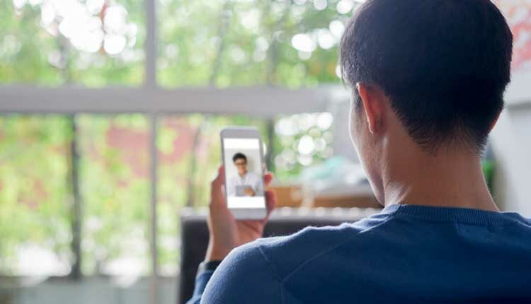 close up rear view of young man using smartphone to video conference to consulting about male hormone and physical with specialist and listen explaining at home for telemedicine health technology life concept