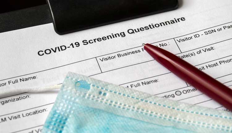 COVID-19 Screening Questionnaire form with medical mask and a pen on it. Healthcare and medical concept. Closeup