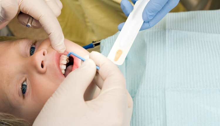 Child Boy Receiving Fluoride Treatment from Dentist