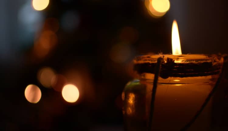 Candle flame in the evening with warm lights in the background