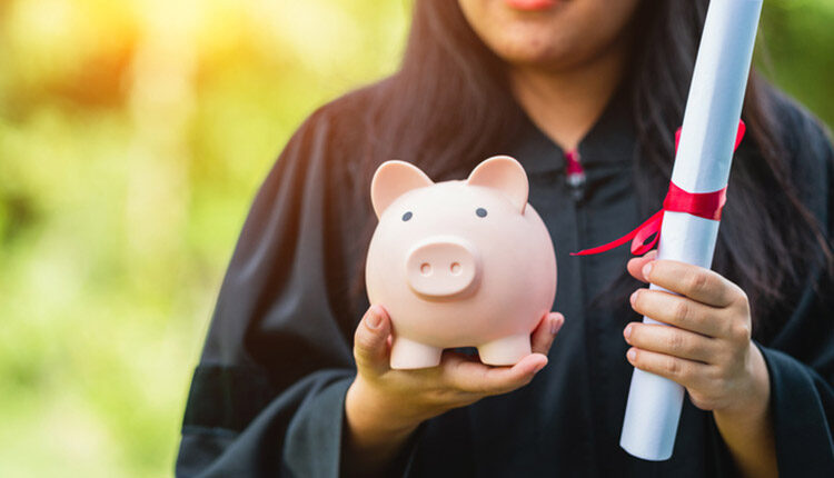 Graduate holding piggy bank