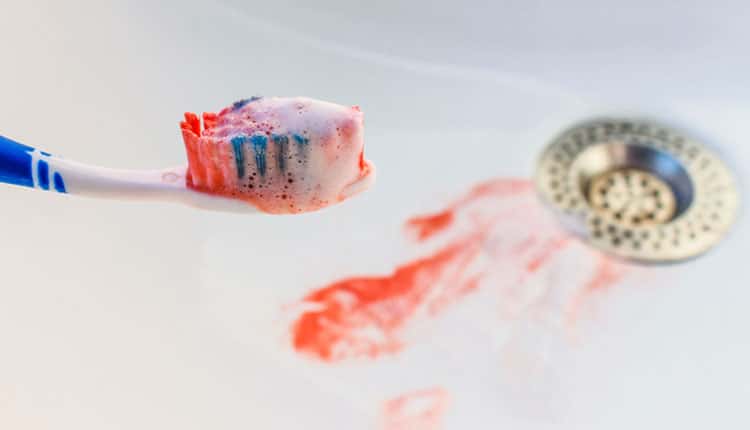 Blood on the toothbrush on background of sink