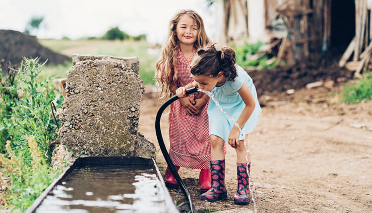 Little girls drinking water from a hose