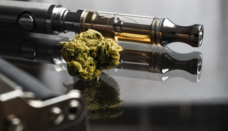 Close up shot of real cannabis or weed with cannabis oil in cartridge of vape pen in the background, roller blurred in foreground and text space on the right under the dark theme