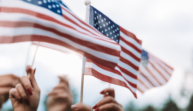 Group of people holding small United States’ national flags in the air.