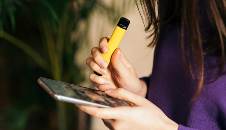 Yellow disposable electronic cigarette in a woman's hand