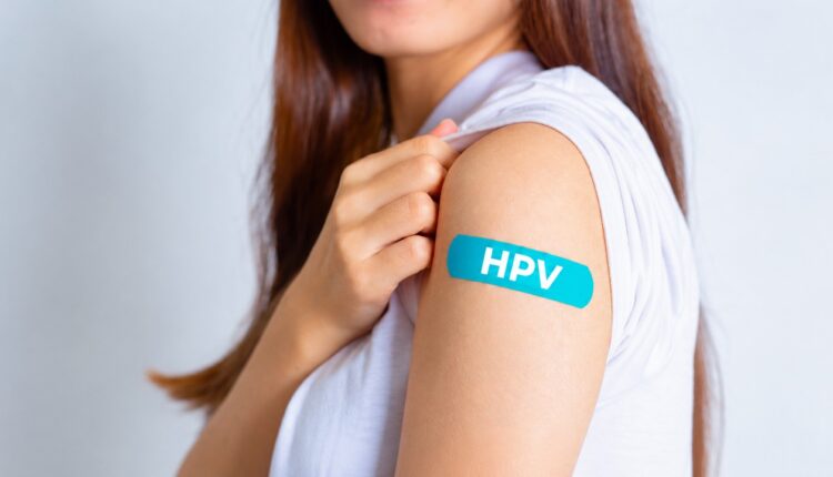 Young woman showing a blue HPV bandage on her upper arm after vaccination
