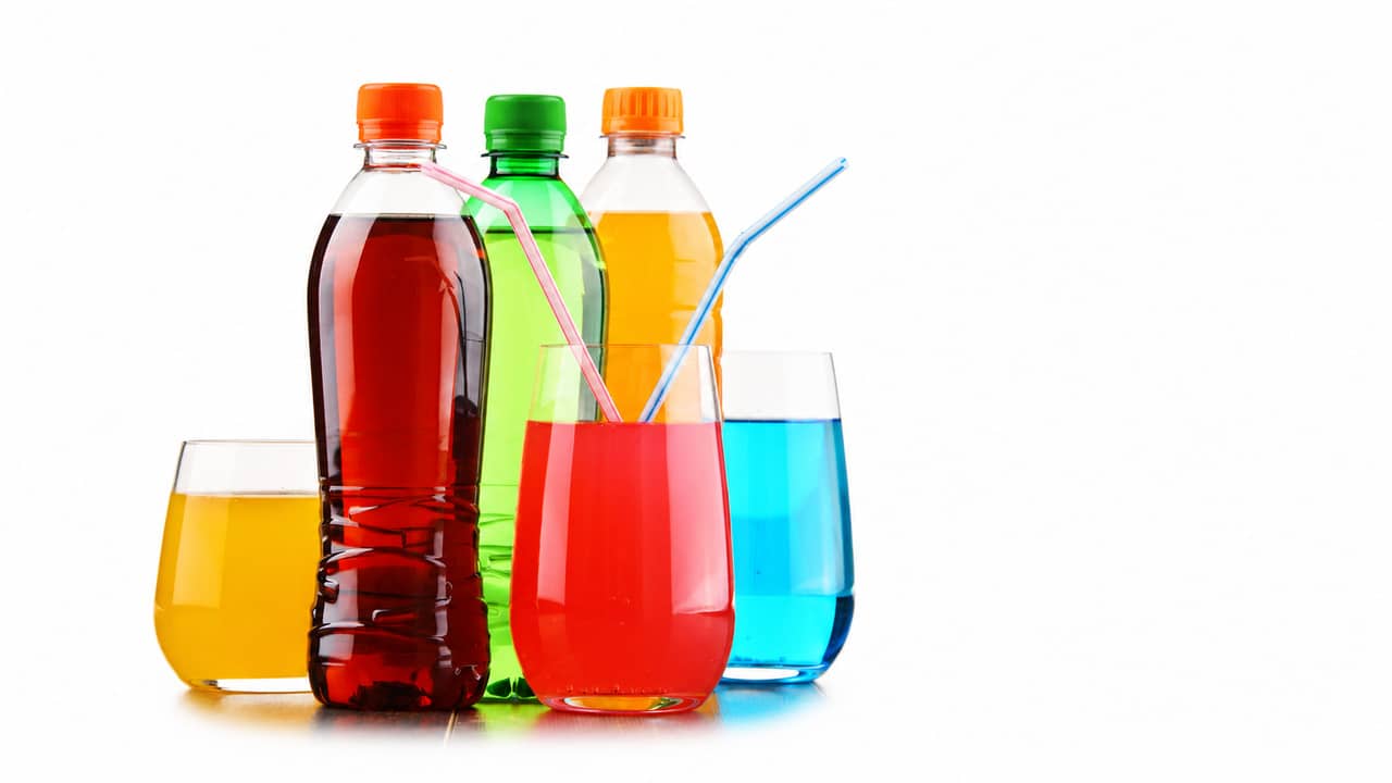 Bottles and glasses of colorful carbonated soft drinks